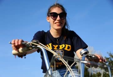 woman in black and yellow crew neck t-shirt riding bicycle during daytime