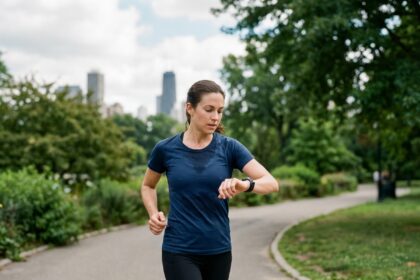 Femme sportive courant en ville en regardant sa montre connectée