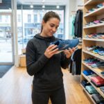 Jeune femme sportive inspectant une chaussure de course en magasin