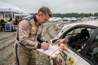 Pilote et copilote de rallye consultant le calendrier des manches 2026 mis à jour dans le paddock du service park