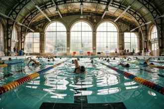 Piscine intérieure municipale parisienne avec nageurs de club s'entraînant dans les couloirs lors d'une séance matinale à la piscine Butte aux Cailles